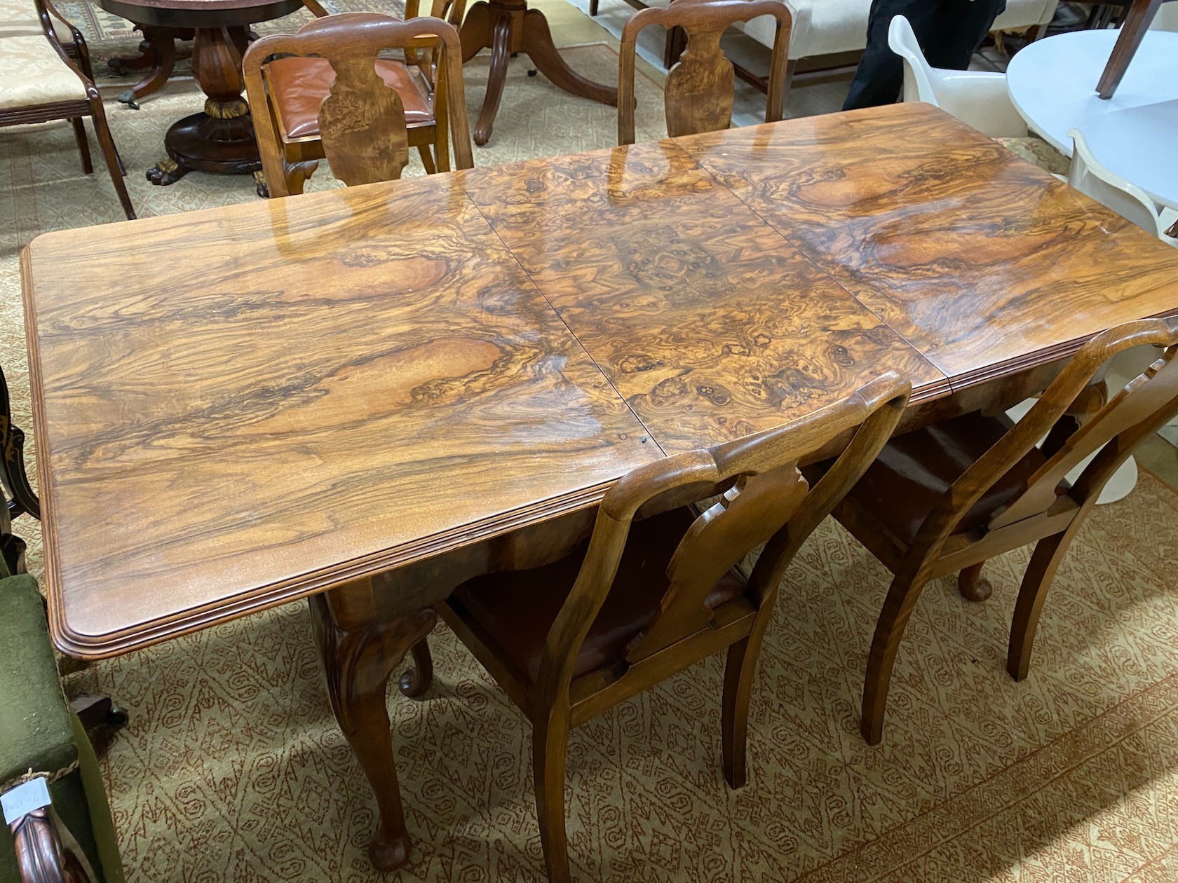 A Queen Anne revival figured walnut extending dining table, length 183cm extended, one spare leaf, width 83cm, height 75cm and six chairs, two with arms